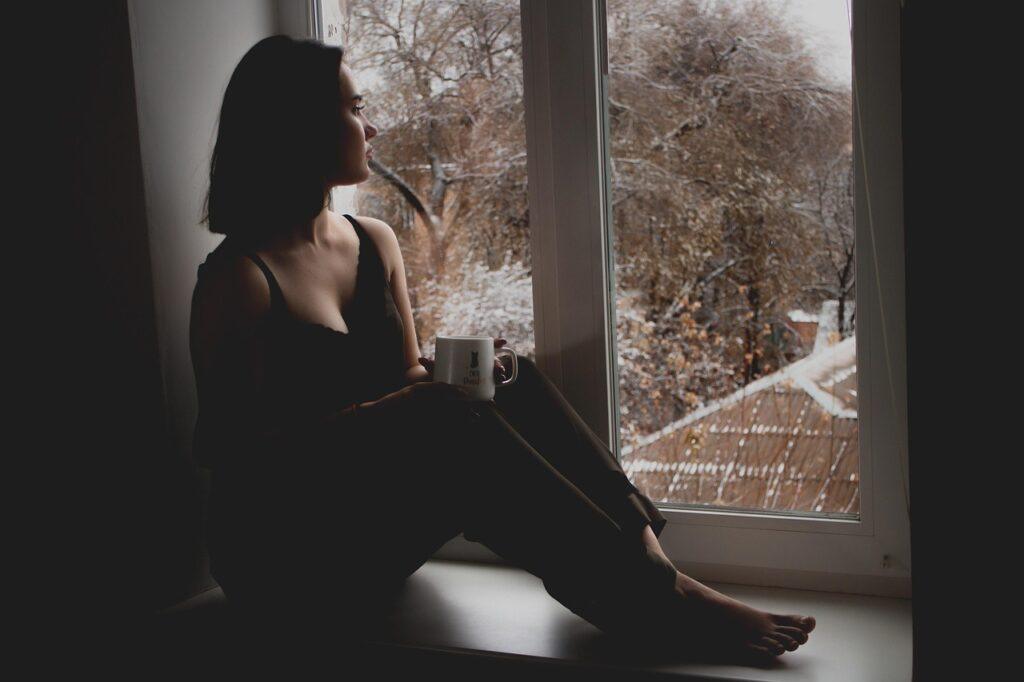 girl, sad girl, window, sit, sitting, wait, waiting, by the window, looking out, cup, mug, indoors, woman, model, sad, person, brunette, female, young woman, thinking, lady, depression, melancholy, tired
