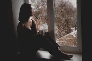 girl, sad girl, window, sit, sitting, wait, waiting, by the window, looking out, cup, mug, indoors, woman, model, sad, person, brunette, female, young woman, thinking, lady, depression, melancholy, tired