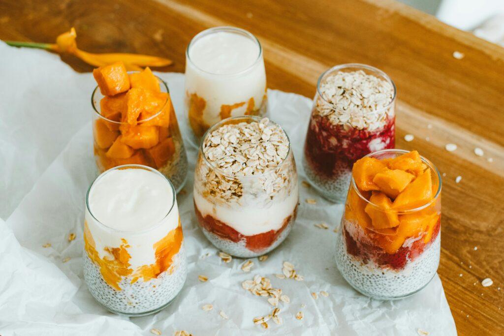 Colorful fruit and yogurt parfaits in glasses with oats, perfect for a healthy breakfast.