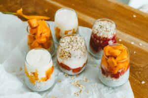 Colorful fruit and yogurt parfaits in glasses with oats, perfect for a healthy breakfast.