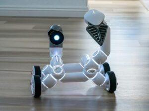 Close-up of a wheeled robot toy with a spotlight in an indoor setting, showcasing modern technology.